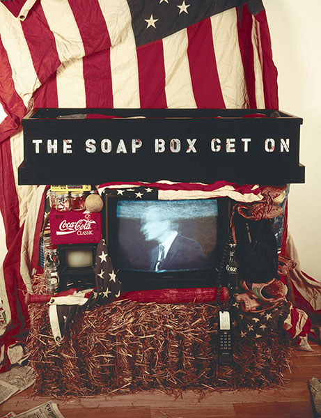 Get on the Soap Box, 1992, installation view, C-Prints, gelatin silver prints, wood light box, video, hay bale, flags, found objects, 48 x 96 x 36